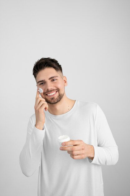 Front view smiley man using face cream