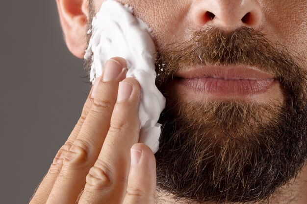 Front view smiley man using shaving cream