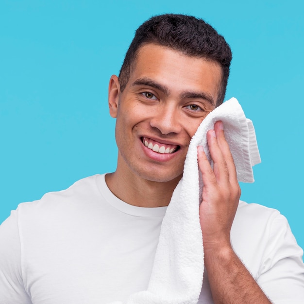 Free photo front view of smiley man using towel on his face