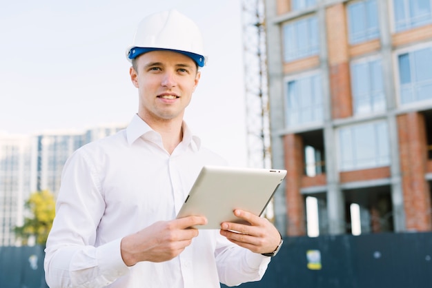 Front view smiley man with tablet and helmet