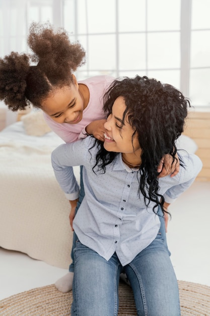 Front view of smiley mother playing at home with her daughter