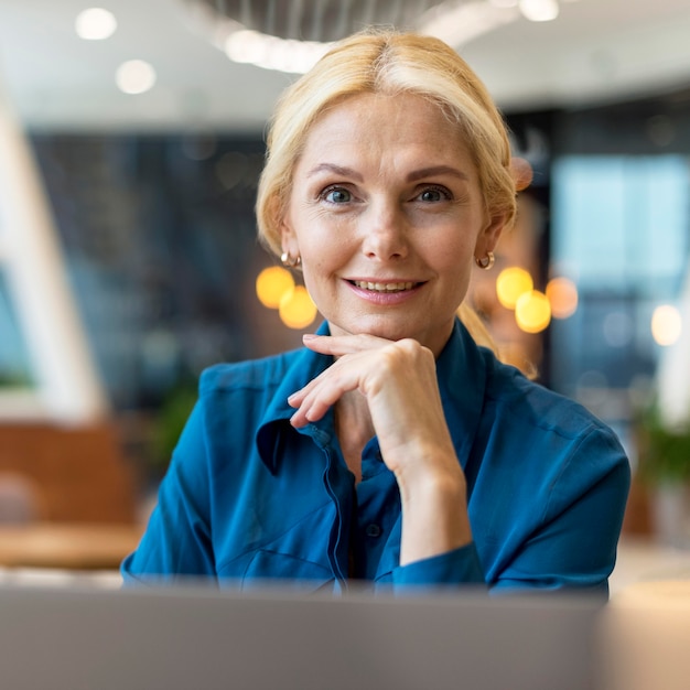 Free photo front view of smiley older business woman posing at a diner