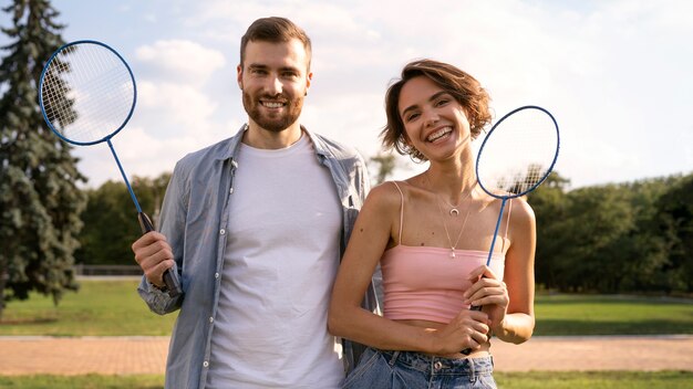 Free photo front view smiley people holding rackets