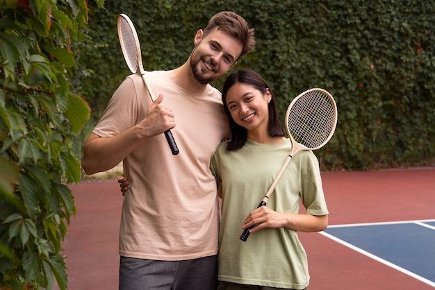 Front view smiley people holding rackets