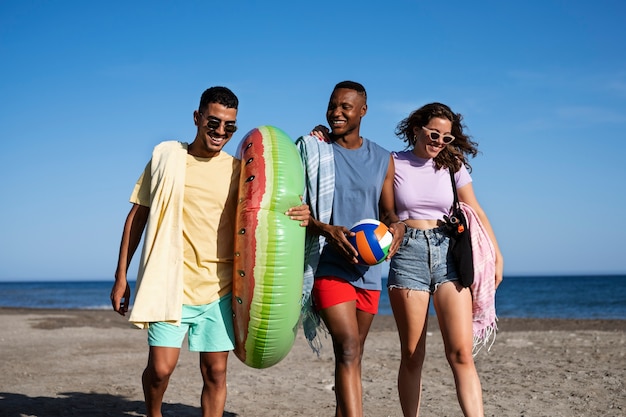 Foto gratuita gente sorridente di vista frontale che cammina sulla spiaggia