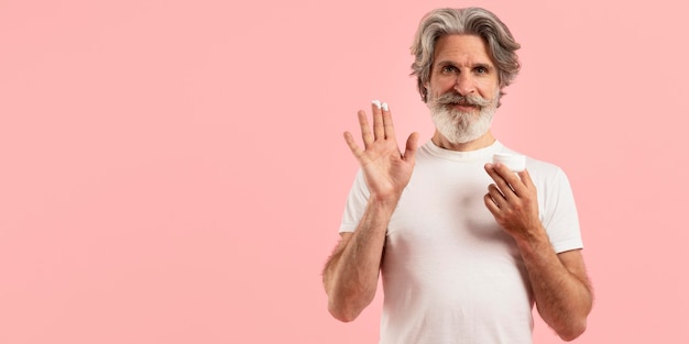 Front view of smiley senior man with beard holding cream