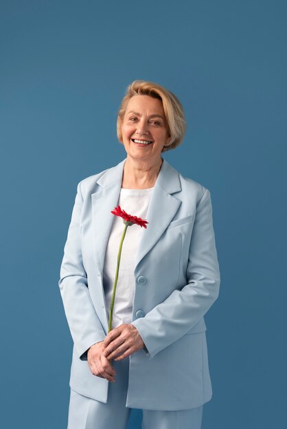 Front view smiley senior woman holding flower