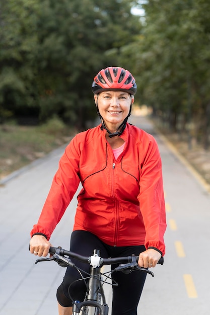 Front view of smiley senior woman outdoors riding bicycle