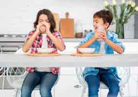 Free photo front view smiley siblings eating together