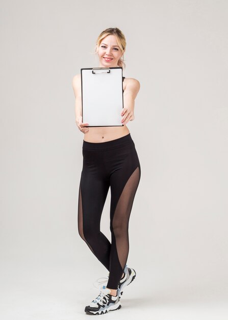 Front view of smiley sporty woman holding notepad