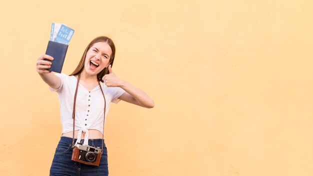 Front view of smiley tourist woman with passport and camera