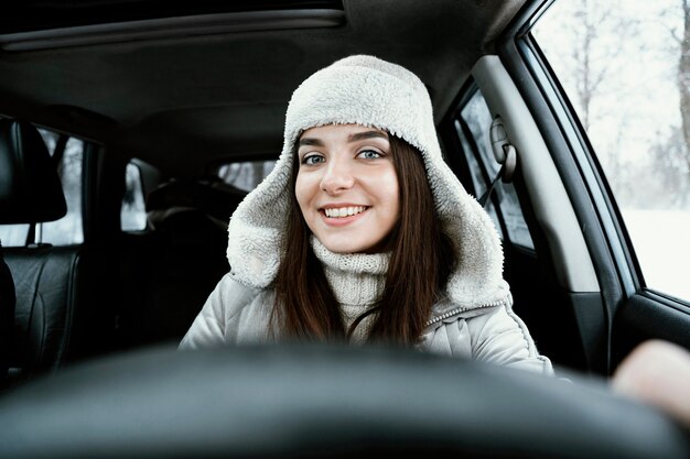 ロードトリップで車を運転する笑顔の女性の正面図