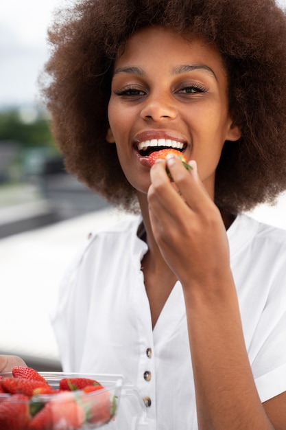 Foto gratuita donna di smiley di vista frontale che mangia le fragole