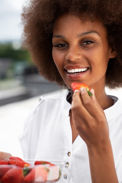 Foto gratuita donna di smiley di vista frontale che mangia le fragole