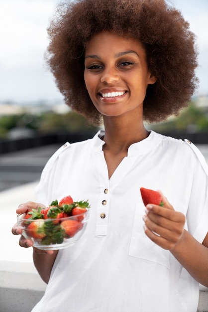 Front view smiley woman eating strawberries