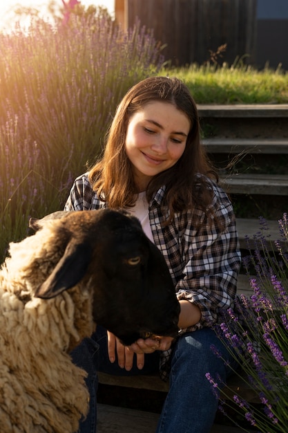 Free photo front view smiley woman feeding sheep