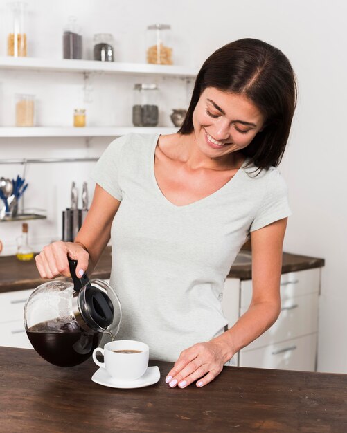 Front view of smiley woman having coffee at home