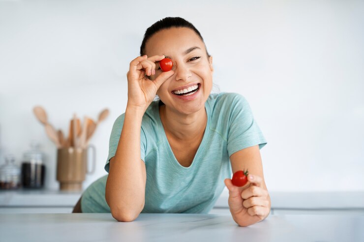 Free Photo front view smiley woman holding cherry tomatoes
