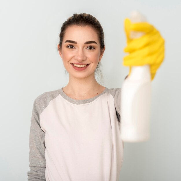 Front view of smiley woman holding cleaning solution
