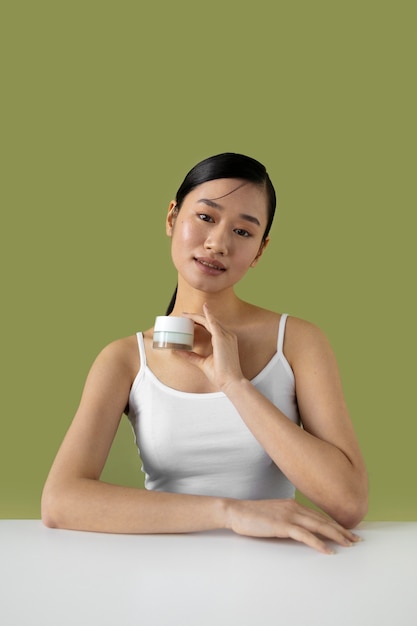 Free photo front view smiley woman holding cream container