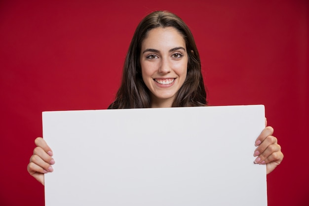 Free photo front view smiley woman holding an empty banner