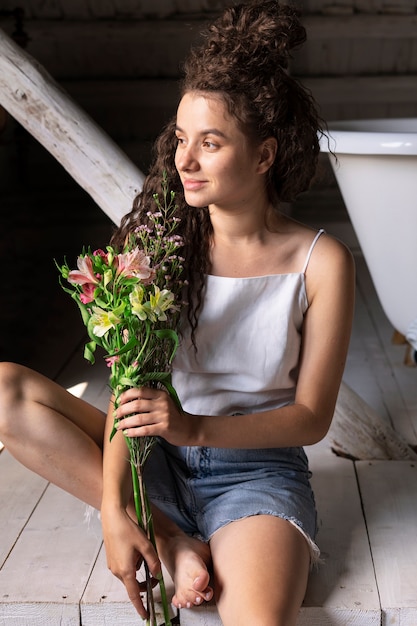 Foto gratuita fiori della holding della donna di smiley di vista frontale