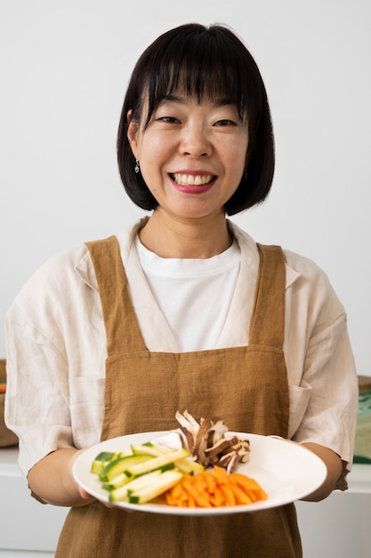 Foto gratuita donna sorridente di vista frontale che tiene piatto di cibo