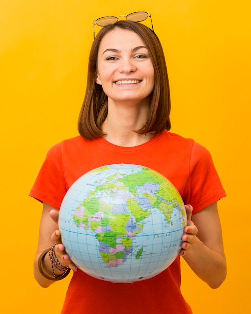 Front view of smiley woman holding globe