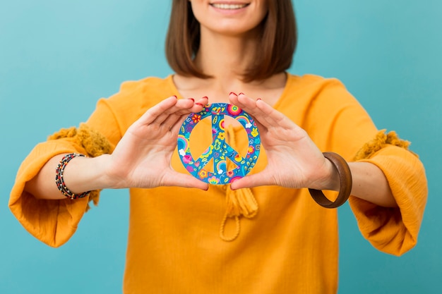 Foto gratuita vista frontale del segno di pace della tenuta della donna di smiley