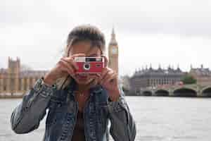 Foto gratuita macchina fotografica della holding della donna di smiley di vista frontale