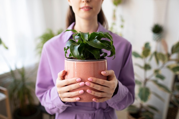 Front view smiley woman holding plant