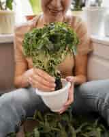 Free photo front view of smiley woman holding pot of plant