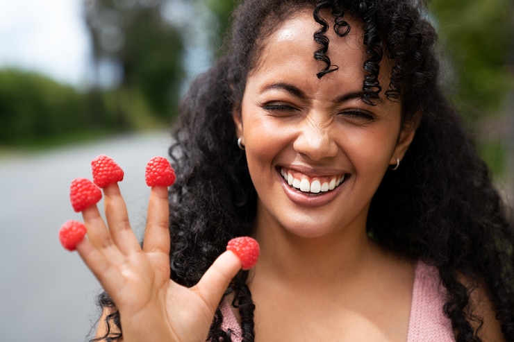 Free Photo front view smiley woman holding raspberries