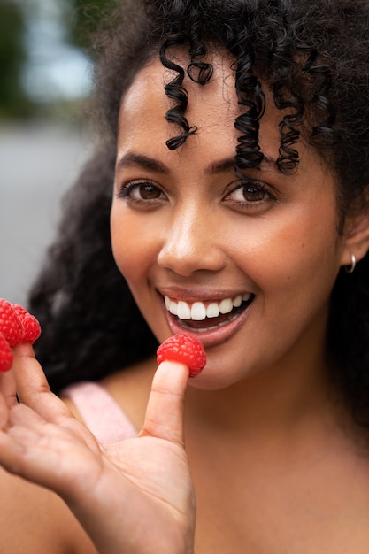 Front view smiley woman holding raspberries