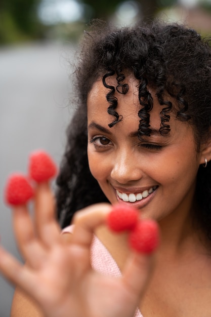 Free photo front view smiley woman holding raspberries