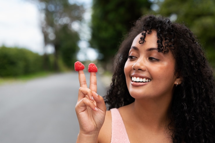 Free Photo front view smiley woman holding raspberries