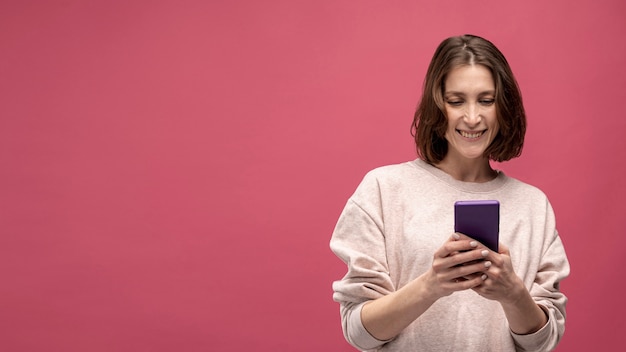 Free photo front view of smiley woman holding smartphone