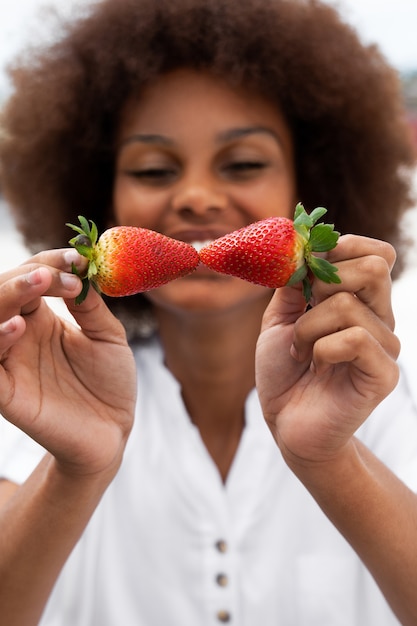 Front view smiley woman holding strawberry