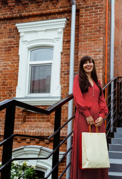 Free photo front view of smiley woman posing outdoors with shopping bags