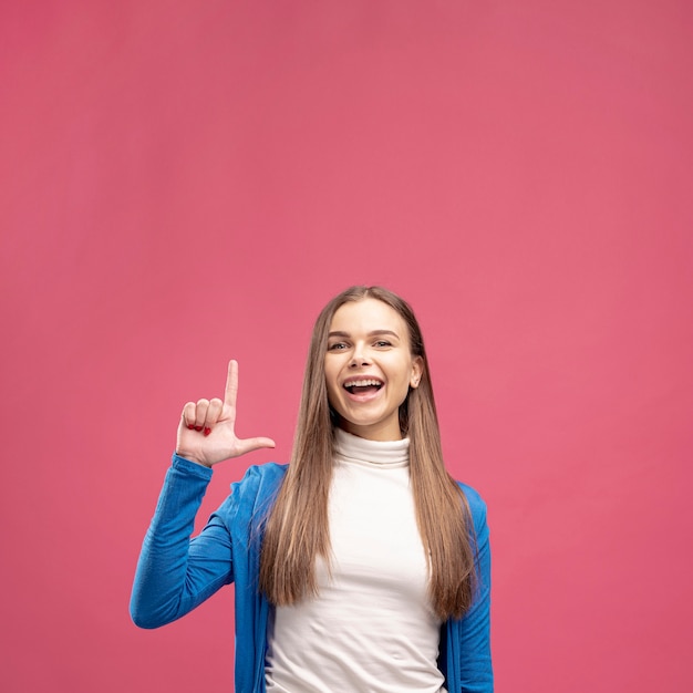 Front view of smiley woman posing and pointing up