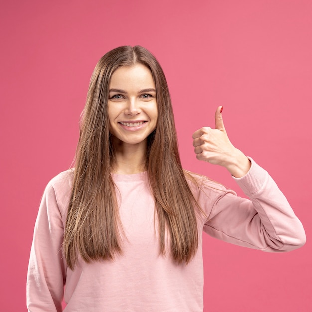 Front view of smiley woman posing while giving thumbs up