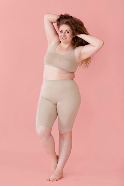 Free photo front view of smiley woman posing while wearing a body shaper