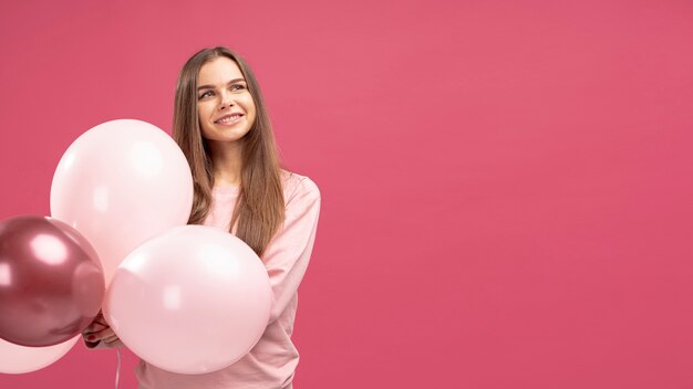 Front view of smiley woman posing with balloons
