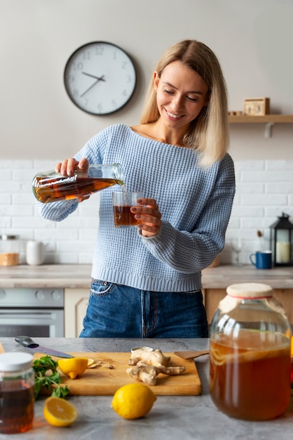 Front view smiley woman pouring kombucha