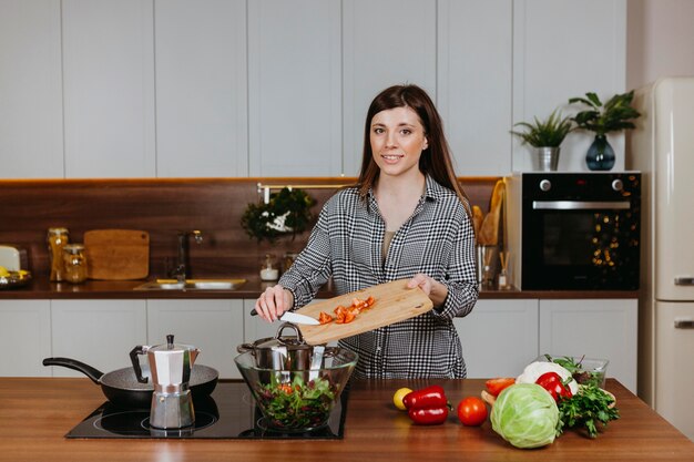 Вид спереди улыбающейся женщины, готовящей еду на кухне