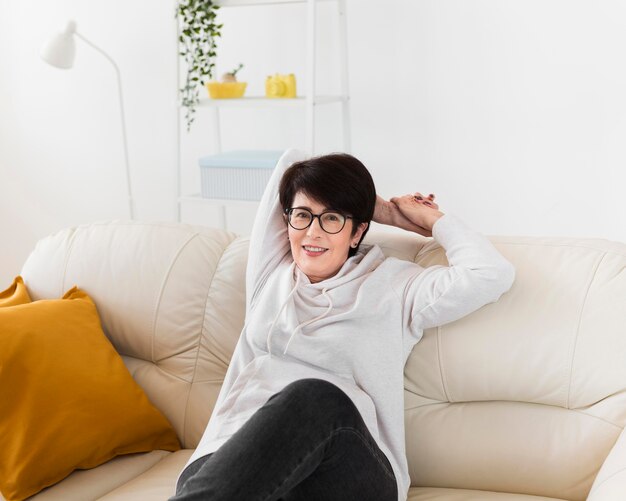 Front view of smiley woman relaxing at home on sofa