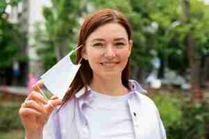 Free photo front view smiley woman taking off mask