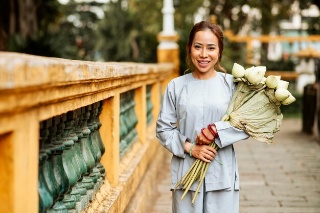 花の花束と寺院で笑顔の女性の正面図