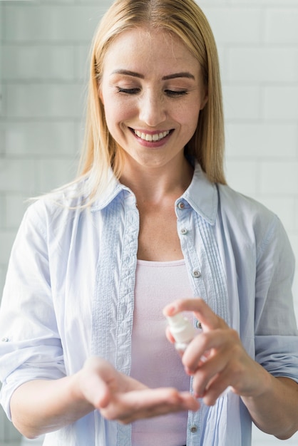 Front view of smiley woman using hand sanitizer