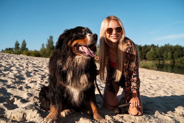 Foto gratuita donna sorridente di vista frontale con il cane sveglio sulla spiaggia